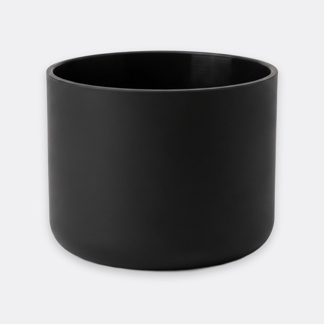 A matte black cylindrical planter or candle holder with a smooth, non-reflective finish, shown against a plain light gray background.