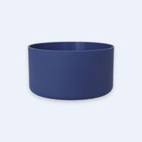 A matte navy blue cylindrical bowl or planter with a smooth finish, shown from a front three-quarter angle on a light gray background.