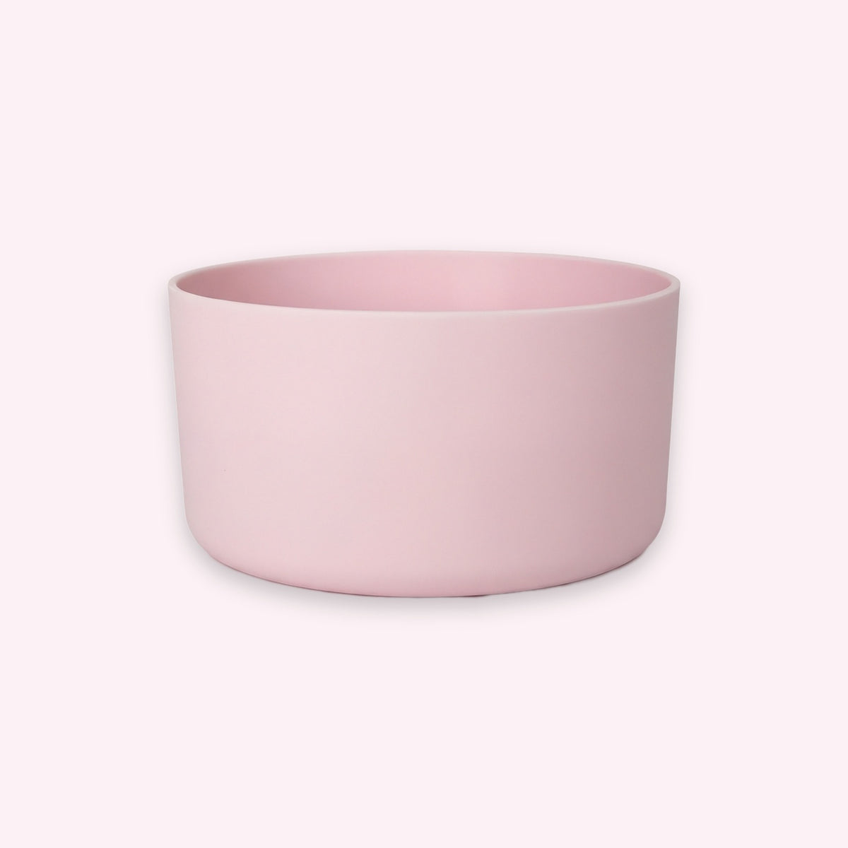 A minimalist, matte light pink cylindrical bowl or planter with a wide rim, shown against a solid pale pink background.