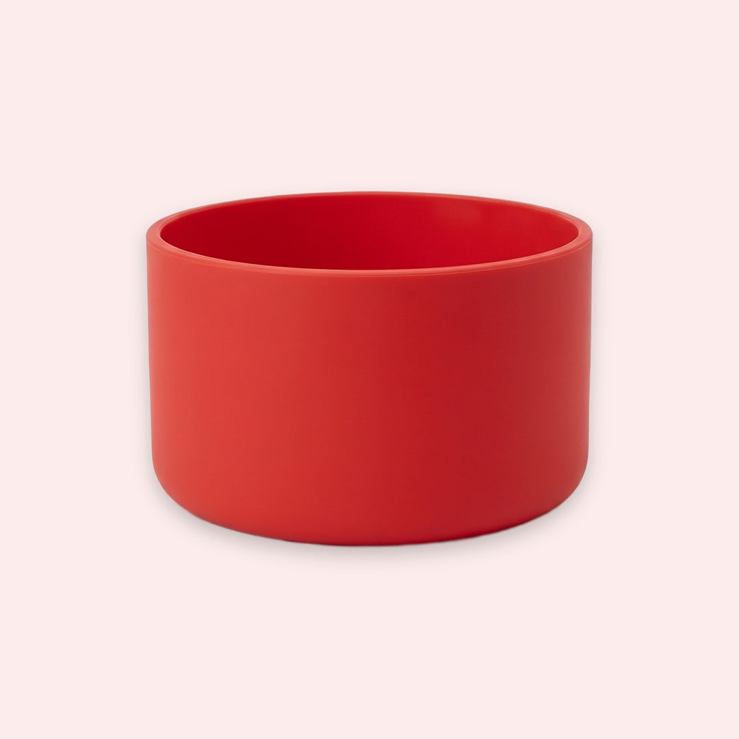A matte red cylindrical bowl or planter with a wide rim, shown on a plain light pink background.