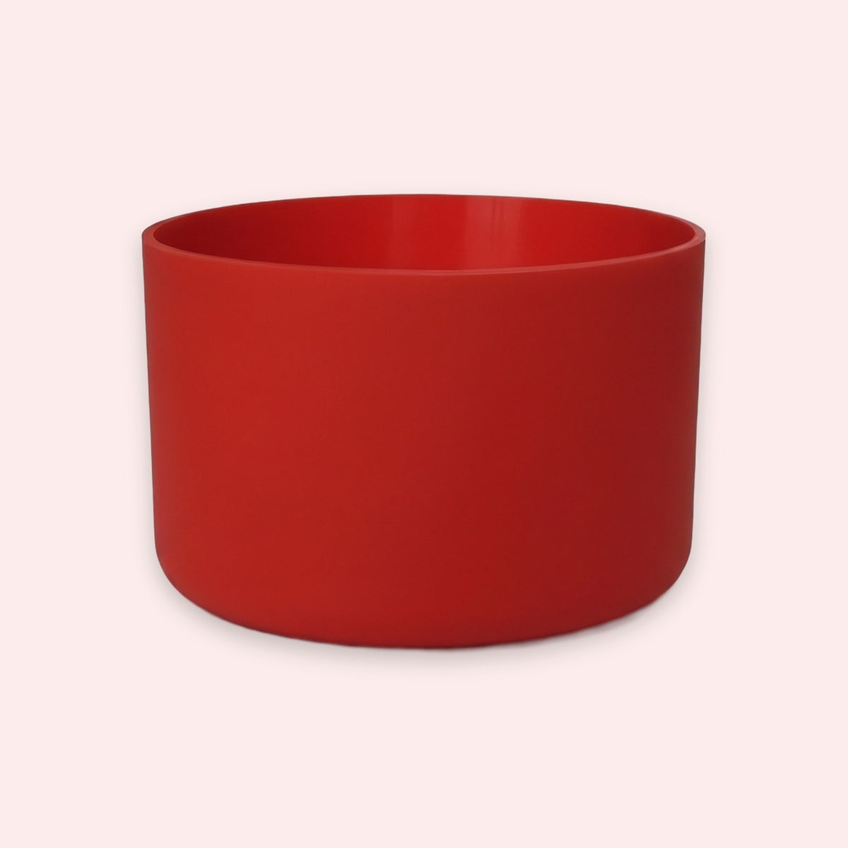 A matte red cylindrical planter or cup with a wide rim, shown against a solid pale pink background.