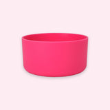 A bright hot pink silicone bowl with a matte finish, shown from a front-facing perspective against a very pale pink background.