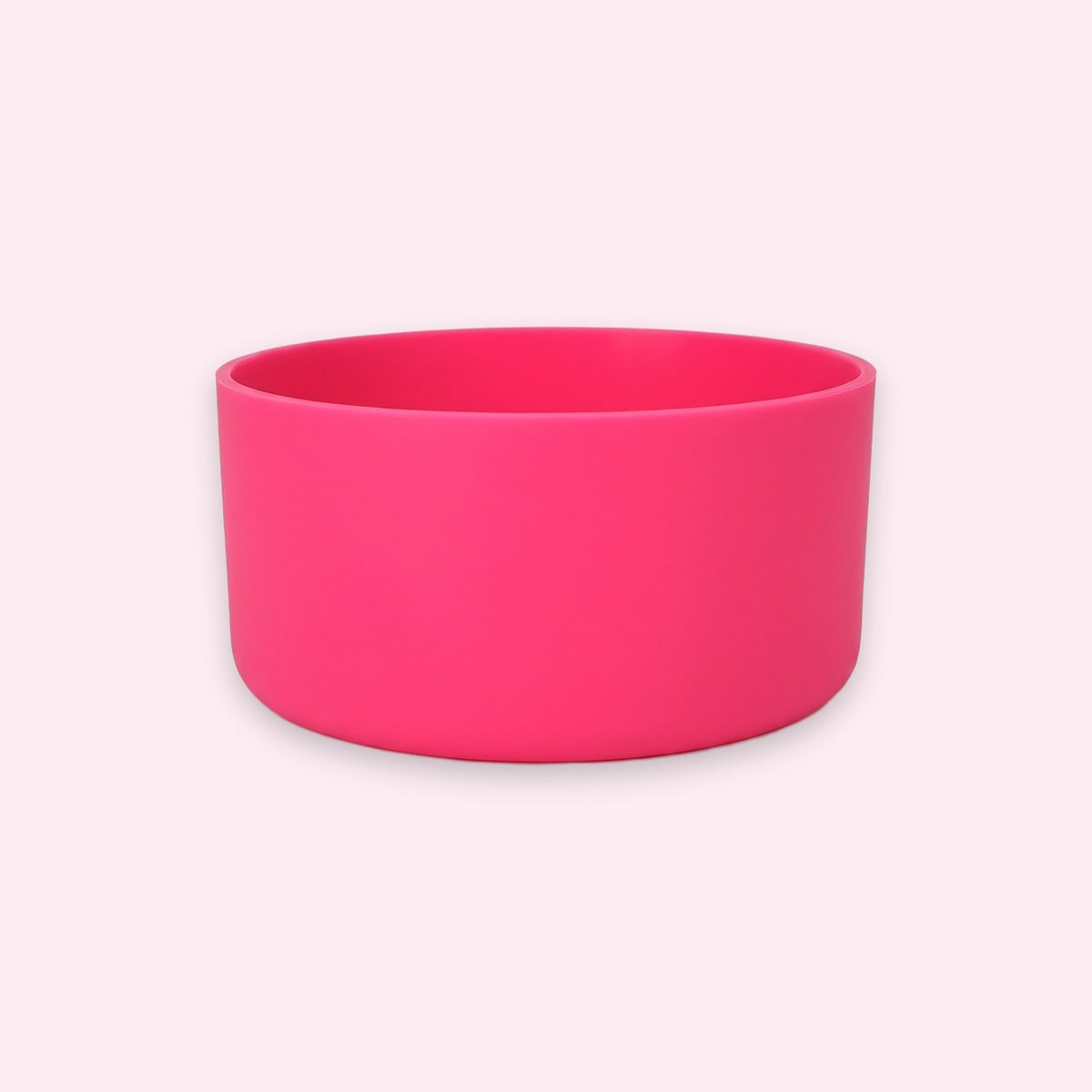 A bright hot pink silicone bowl with a matte finish, shown from a front-facing perspective against a very pale pink background.