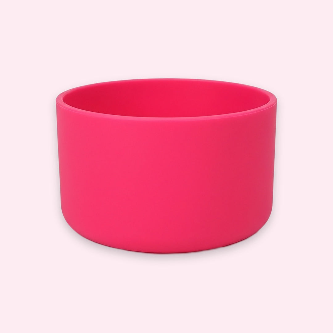 A bright hot pink silicone bowl with a matte finish, shown on a very pale pink background.