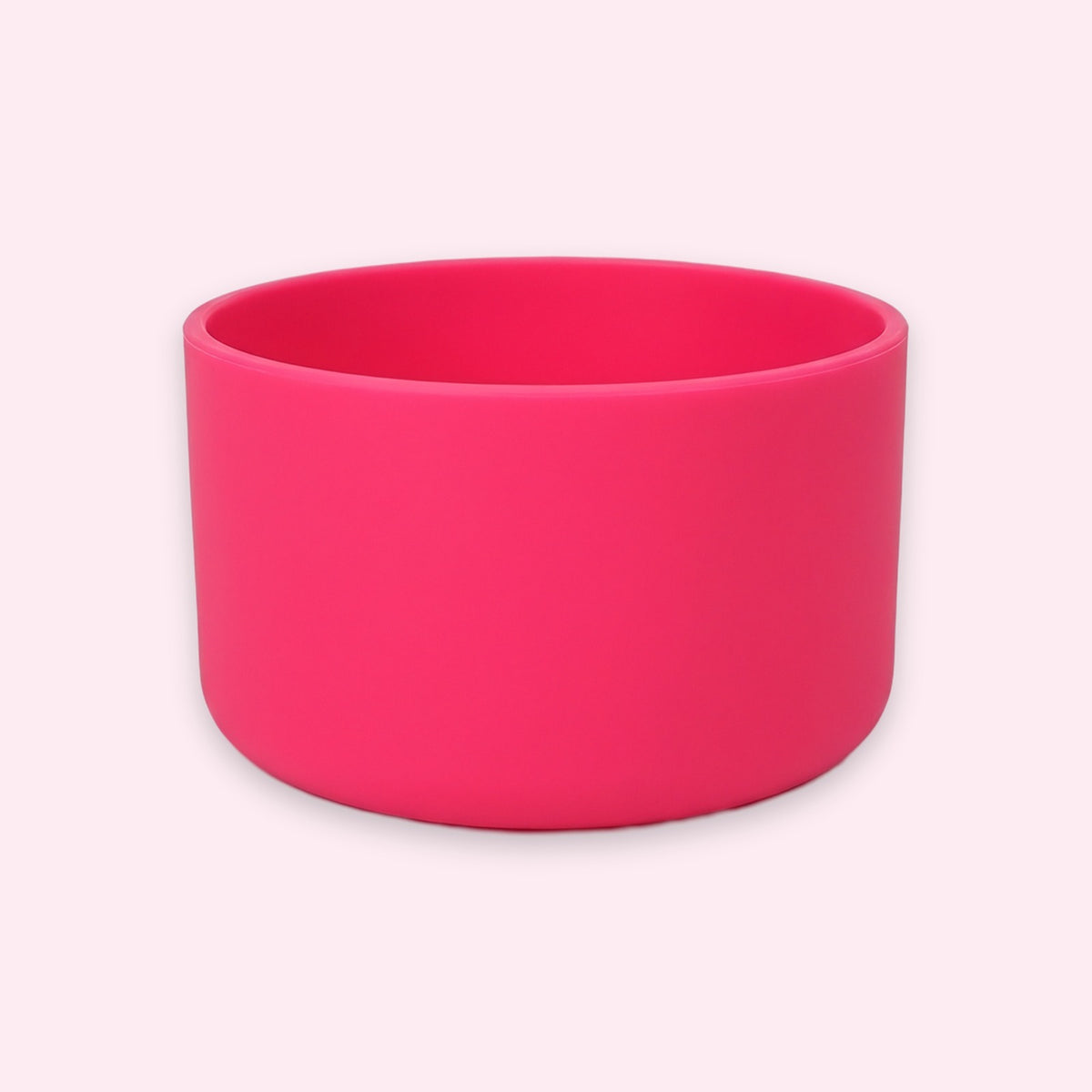 A bright hot pink silicone bowl with a matte finish, shown on a very pale pink background.