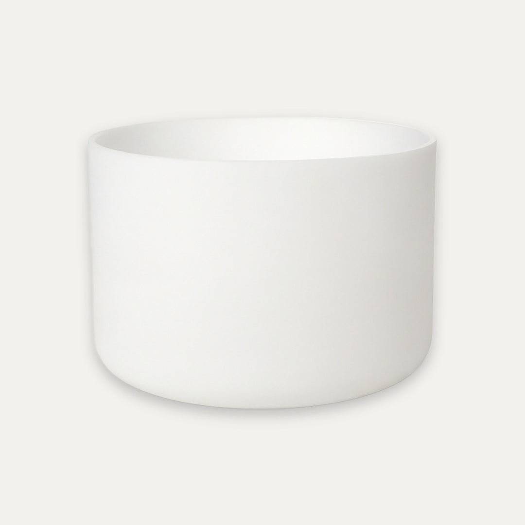 A minimalist white ceramic bowl with a smooth matte finish, centered against a light off-white background.
