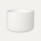 A minimalist white ceramic bowl with a smooth matte finish, centered against a light off-white background.