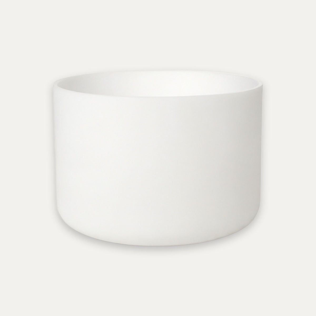 A minimalist white ceramic bowl with a smooth matte finish, centered against a light off-white background.