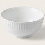 A white ceramic bowl with a textured, dimpled pattern around the outer side, shown on a light beige background.