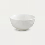 A white ceramic bowl with a textured basketweave pattern on the exterior, shown against a solid off-white background.