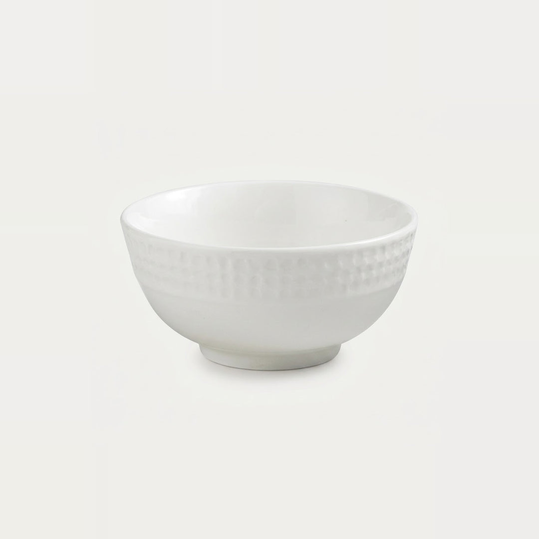 A white ceramic bowl with a textured, dimpled pattern on the exterior, shown against a plain light gray background.