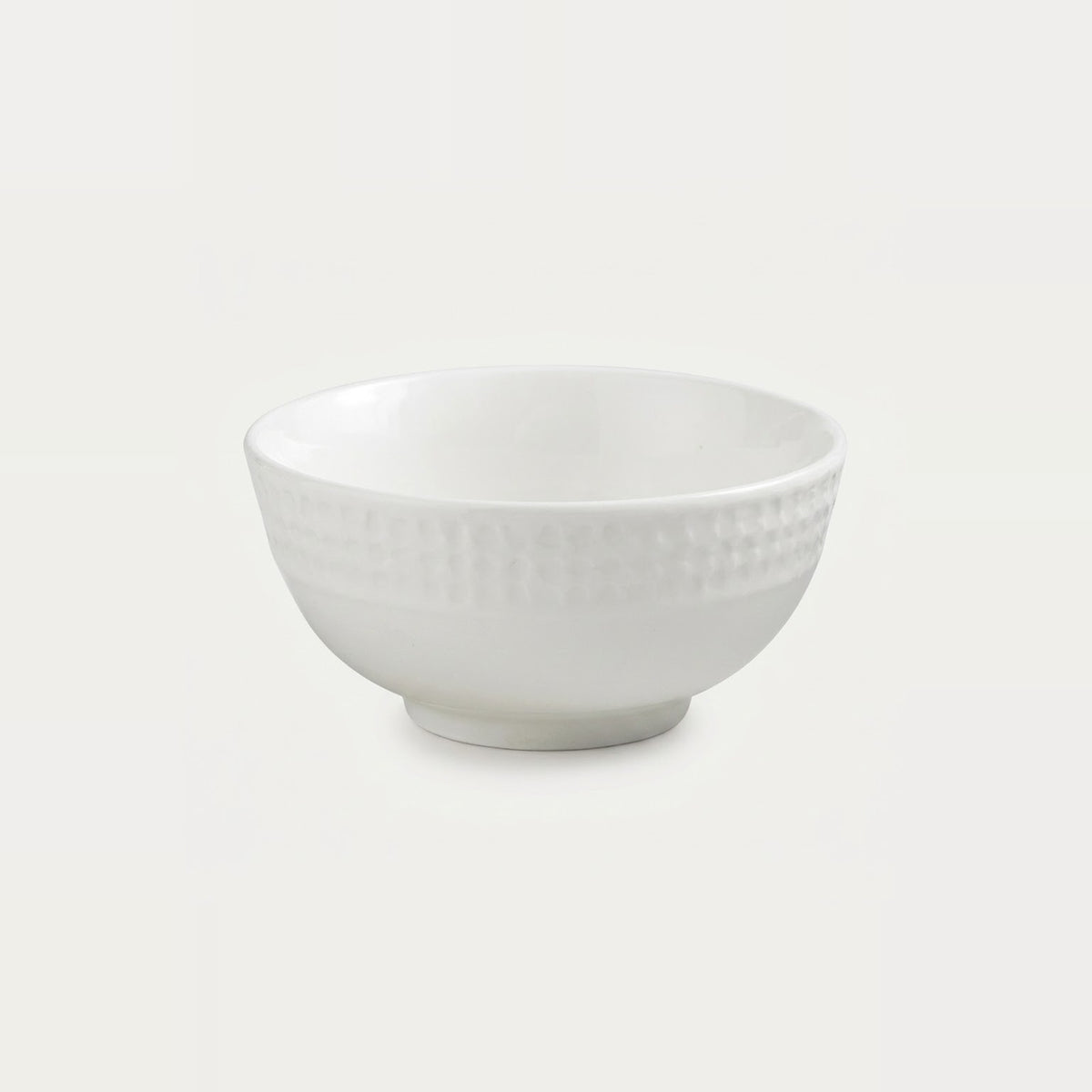 A white ceramic bowl with a textured, dimpled pattern on the exterior, shown against a plain light gray background.