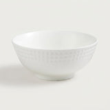 A white ceramic bowl with a textured, dimpled pattern on the exterior, shown against a plain light gray background.