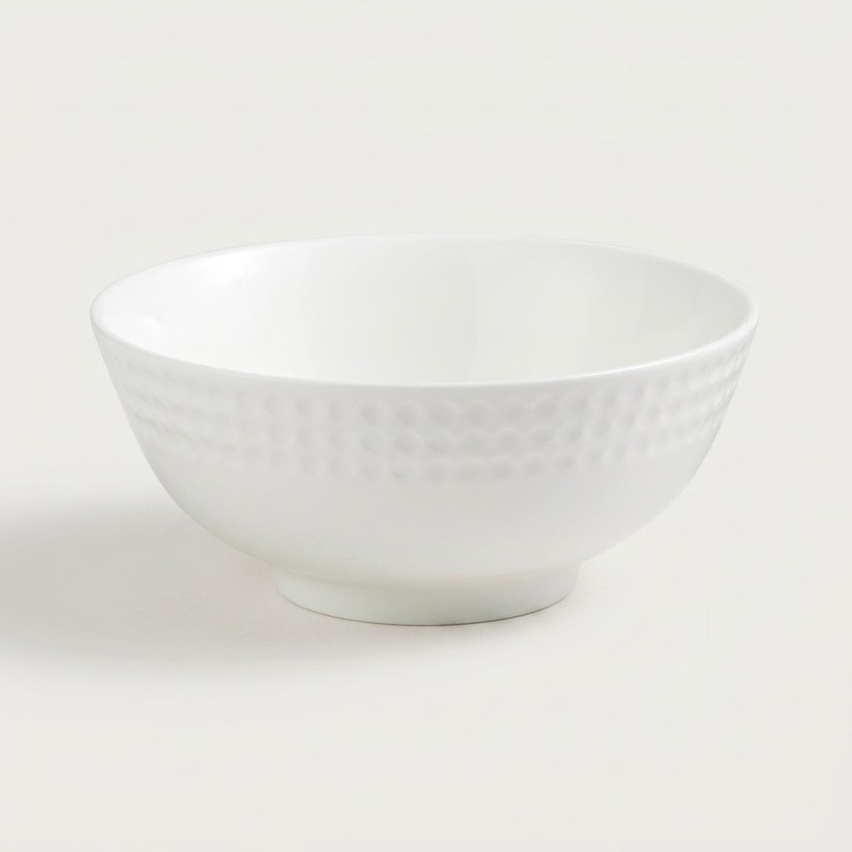 A white ceramic bowl with a textured, dimpled pattern on the exterior, shown against a plain light gray background.