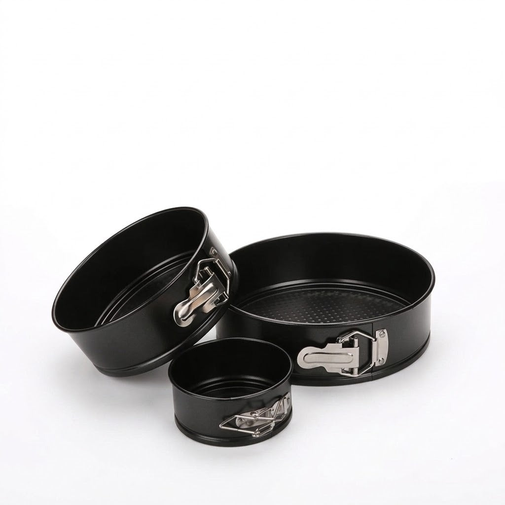 Three black non-stick springform cake pans of different sizes with silver metal clamps, arranged on a clean white background.