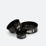 Three-piece black springform cake pan set with silver metal clamps, shown on a light gray background with a small inset image of a decorated two-tier cake.