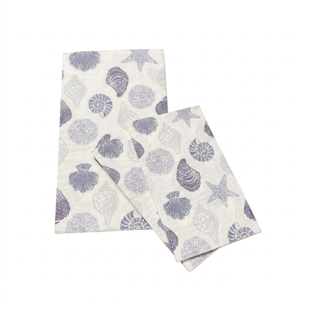 Two cream fabric napkins with grey seashell, starfish, and sand dollar patterns overlap on a white background.