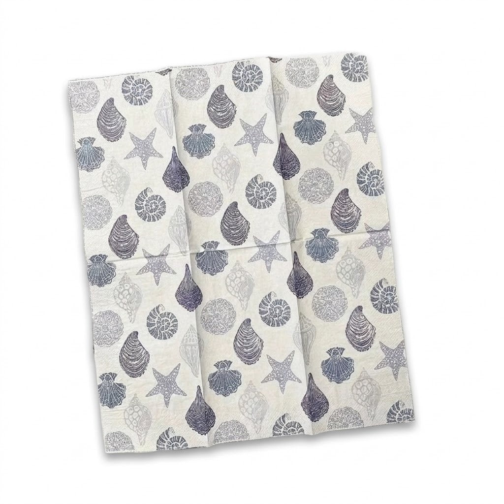 A folded white kitchen towel or napkin featuring a gray and blue-gray seashell and starfish pattern, shown against a plain white background.