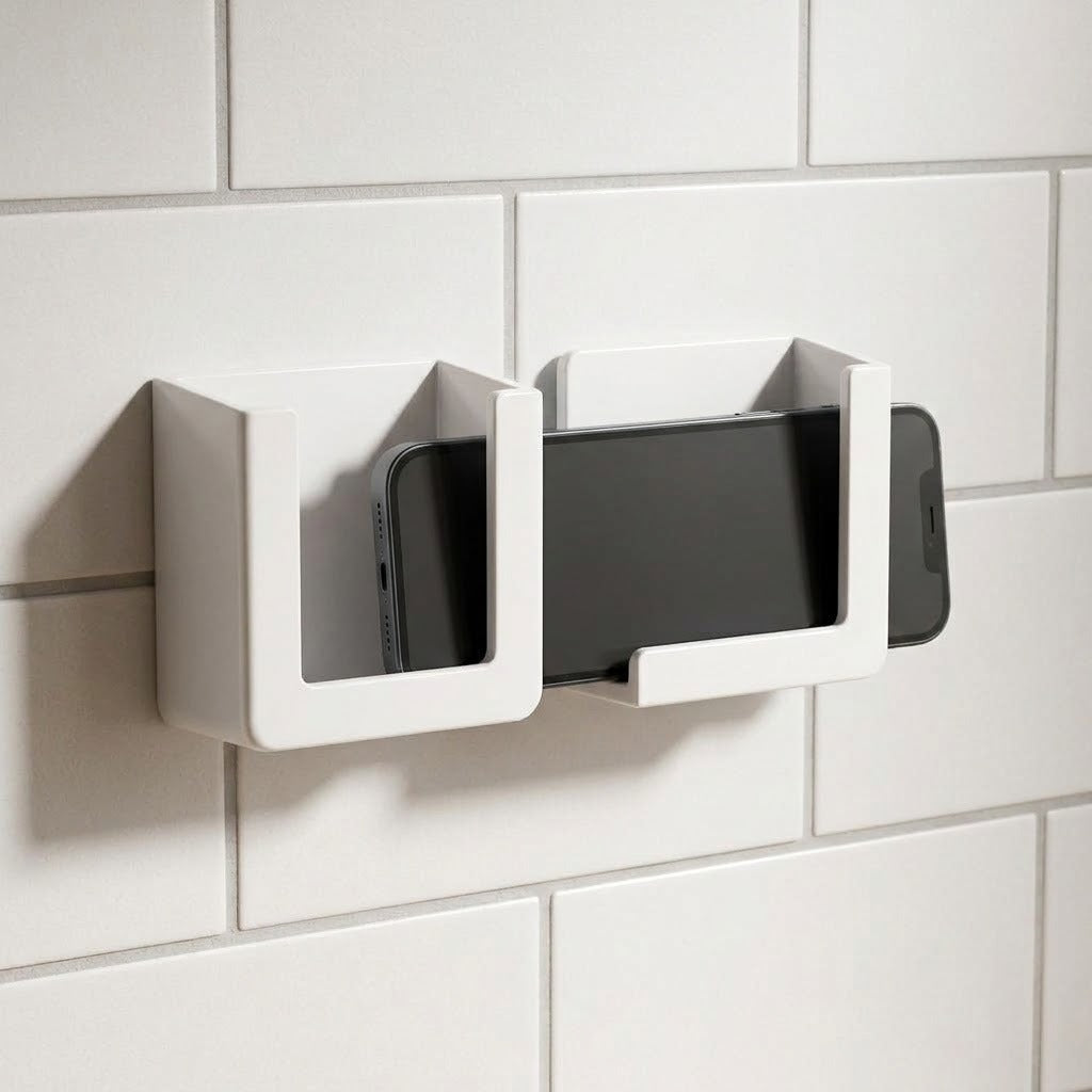 A pair of white wall-mounted phone holders with a smartphone inserted into the right holder, mounted on a white tiled wall.