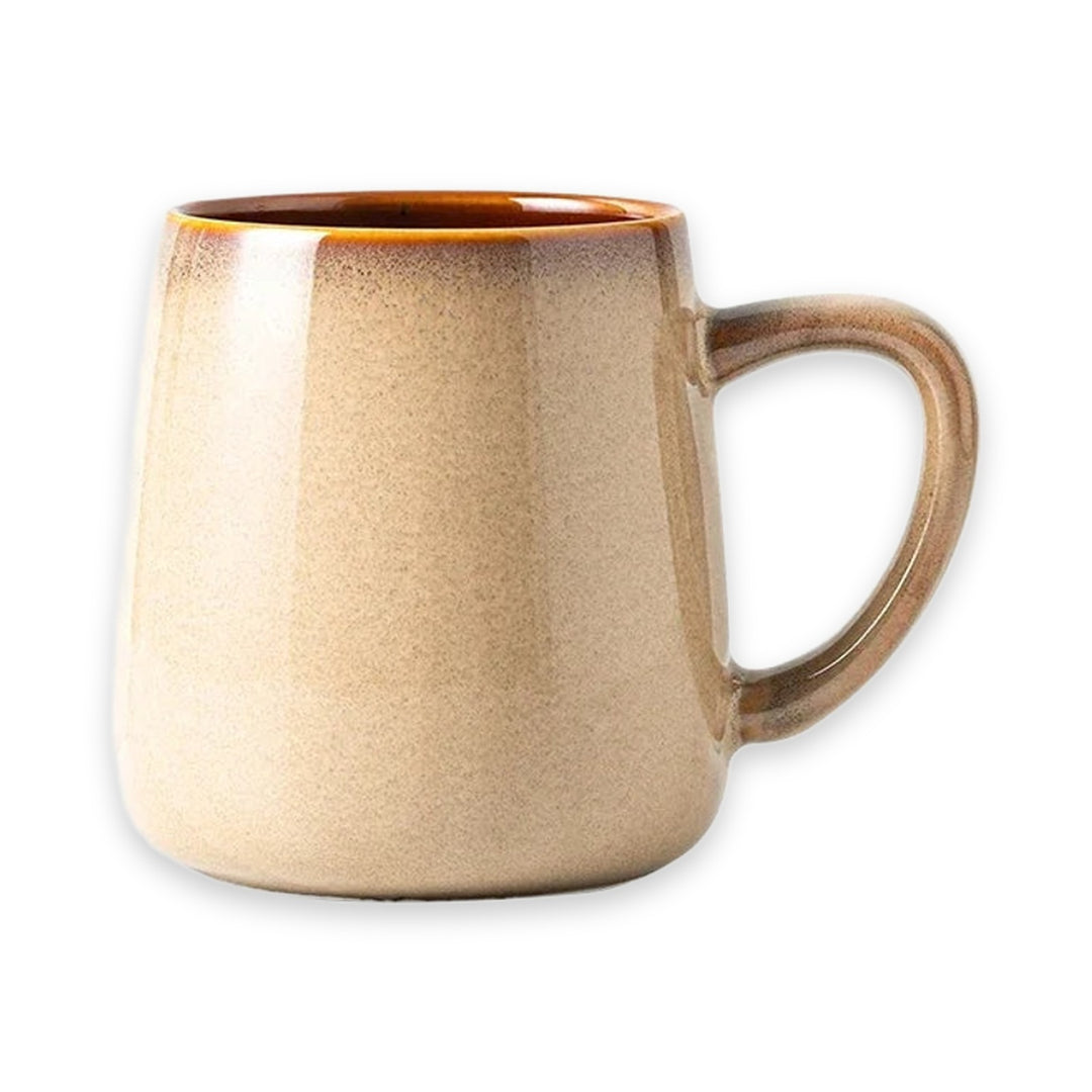 A ceramic mug with a warm beige and brown gradient glaze, featuring a thick C-shaped handle and a glossy finish, shown on a plain white background.