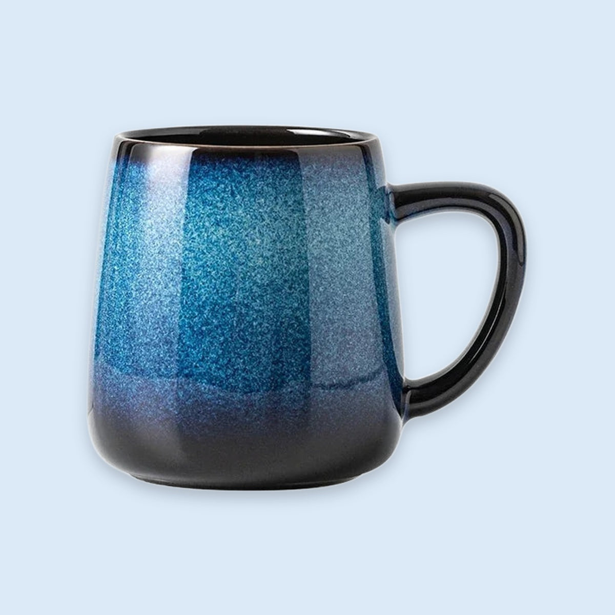 A ceramic coffee mug with a blue and black gradient glaze, shown against a solid light blue background.