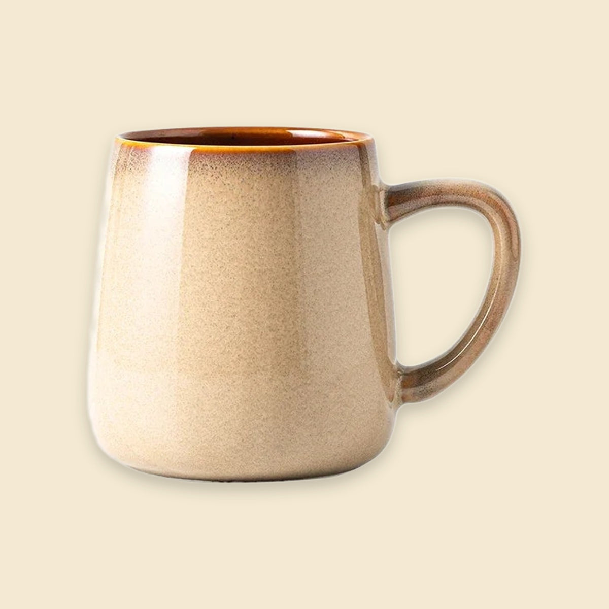 A ceramic coffee mug with a warm beige and brown gradient glaze, featuring a rounded body and a sturdy C-shaped handle, set against a solid cream background.