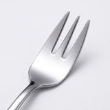 A close-up studio shot of a polished stainless steel dinner fork on a clean, light gray background.