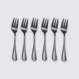 Six dark gray metal forks arranged in a row on a light gray background.