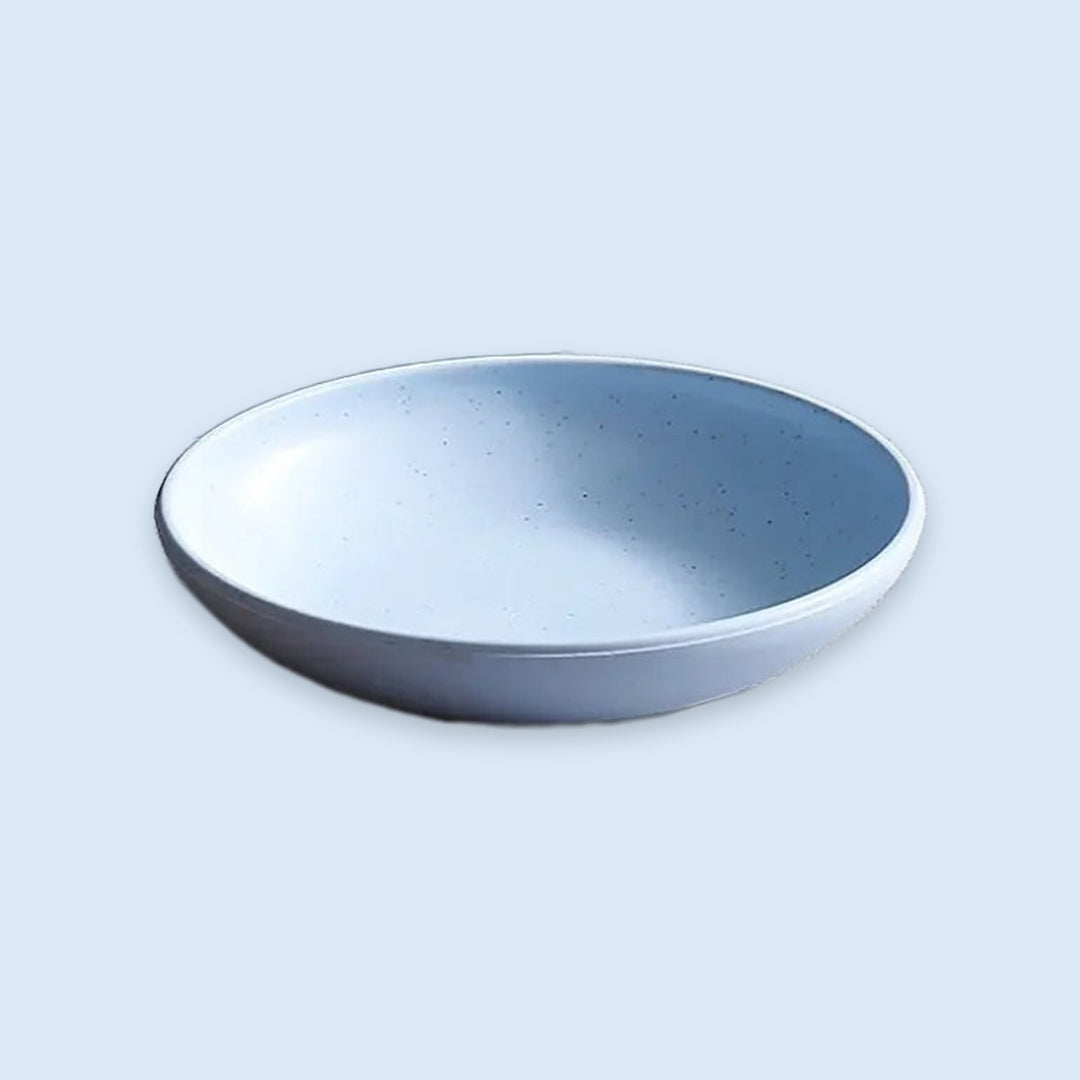 A shallow round ceramic bowl with a speckled light blue and white glaze, shown from a top-down perspective on a light blue background.