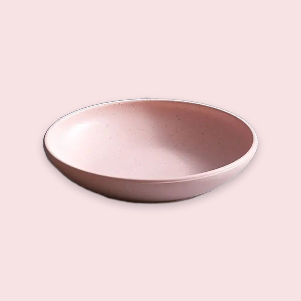 A shallow round ceramic bowl with a speckled off-white glaze and a slightly darker rim, shown on a plain light beige background.
