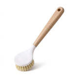 A dish brush with a long wooden handle, white oval head and tan bristles is displayed diagonally against a white background.