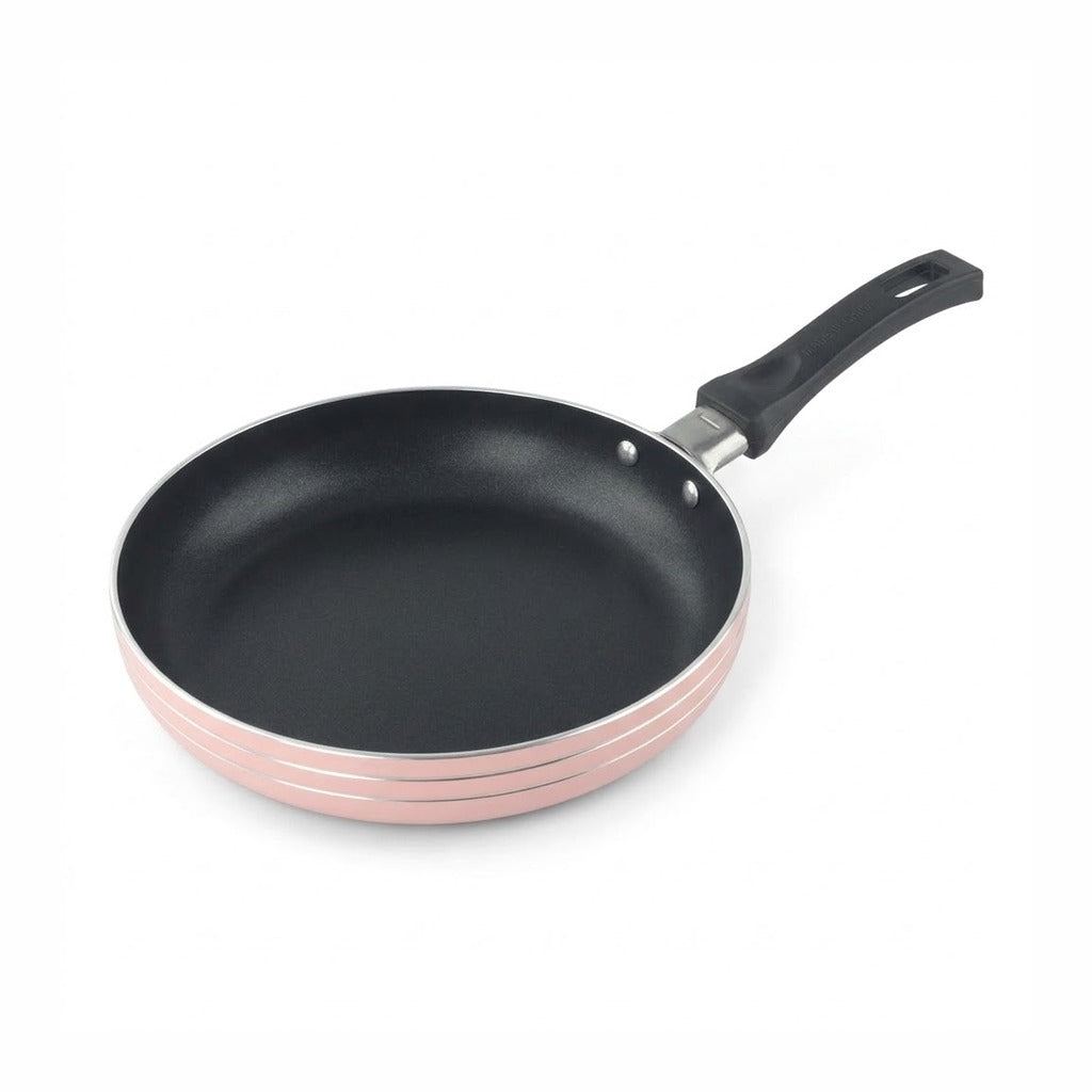 An empty pink frying pan with a black interior, black handle, and silver rim rests against a white background.