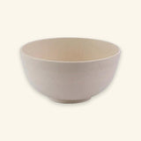 An empty beige speckled bowl with rounded sides and a small circular base sits against a cream background.