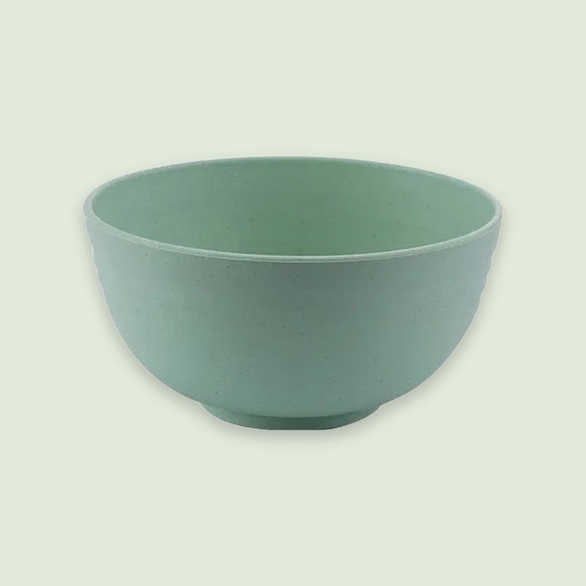 An empty green speckled bowl with rounded sides and a small circular base sits against a pale green background.