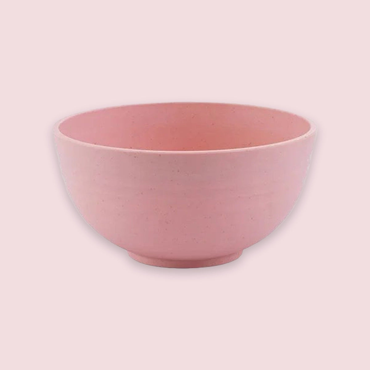 An empty pink speckled bowl with rounded sides and a small circular base sits against a pale pink background.