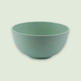 A green bowl with rounded sides and a raised circular base sits against a pale green background.