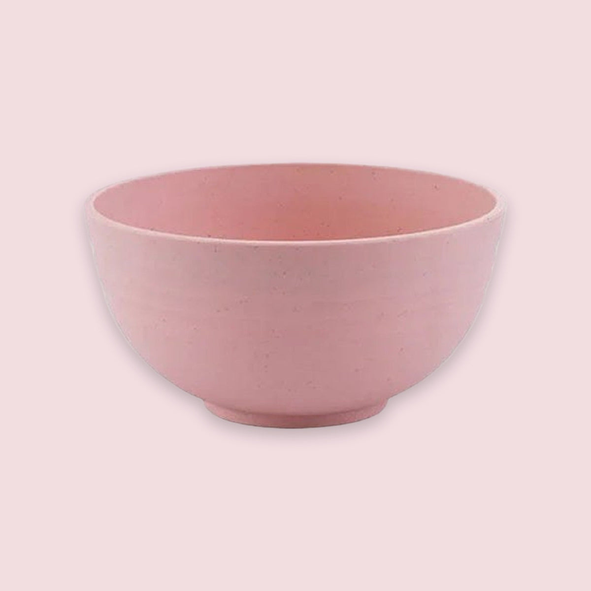 A pink bowl with rounded sides and a raised circular base sits against a pale pink background.