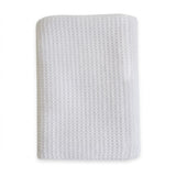 A folded white textured fabric item, likely a baby blanket or swaddle, featuring a waffle or honeycomb pattern, shown on a plain white background.