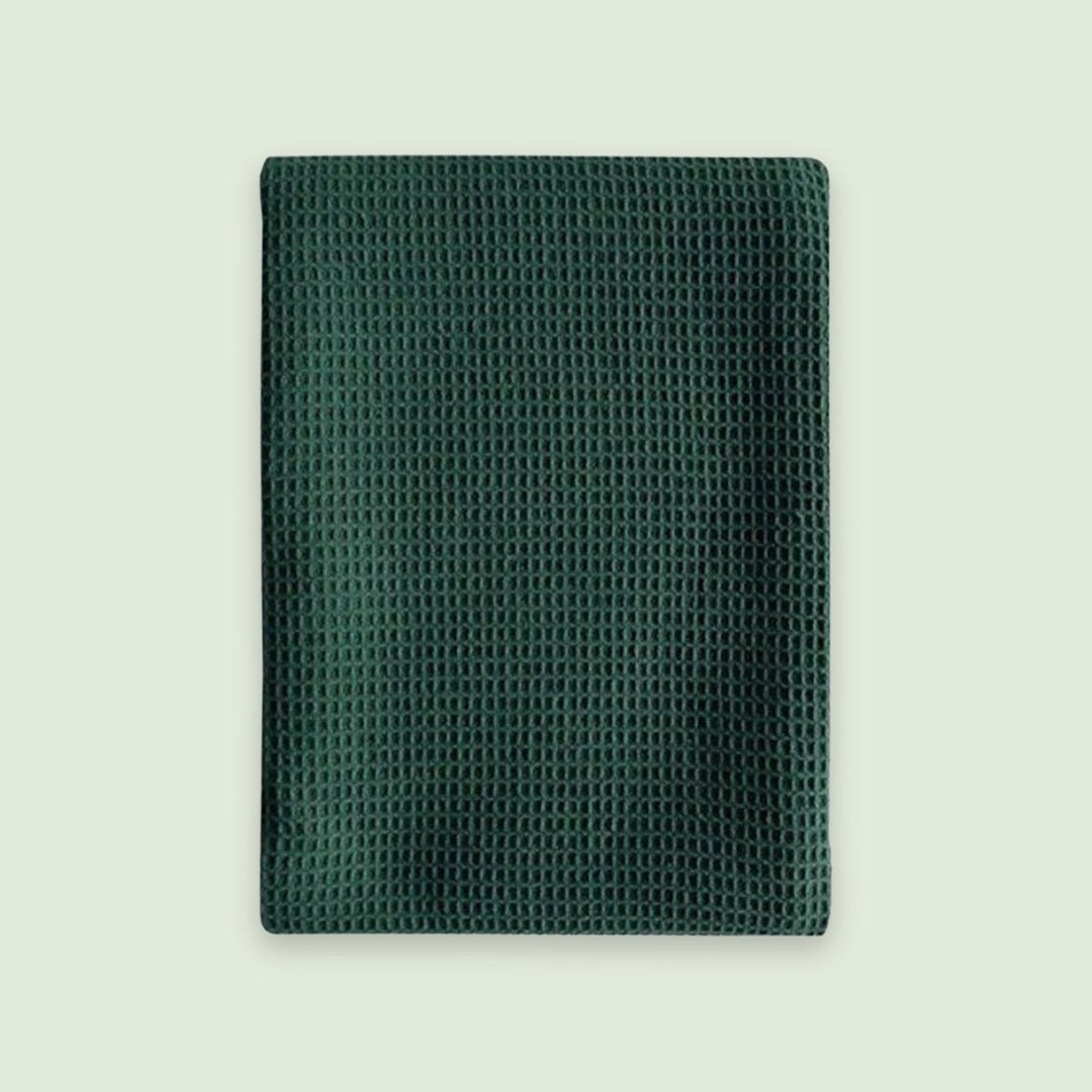 A dark green textured mesh pouch or sleeve with a waffle-like pattern, shown flat against a light off-white background.