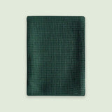 A dark green textured mesh pouch or sleeve with a waffle-like pattern, shown flat against a light off-white background.