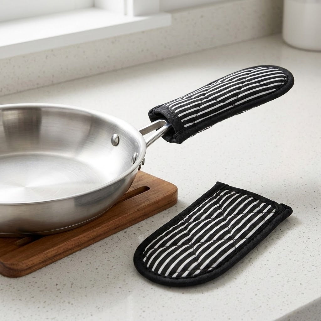 Black and white striped quilted sleeves beside a silver pan on a wooden board, with one sleeve fitted over its handle.