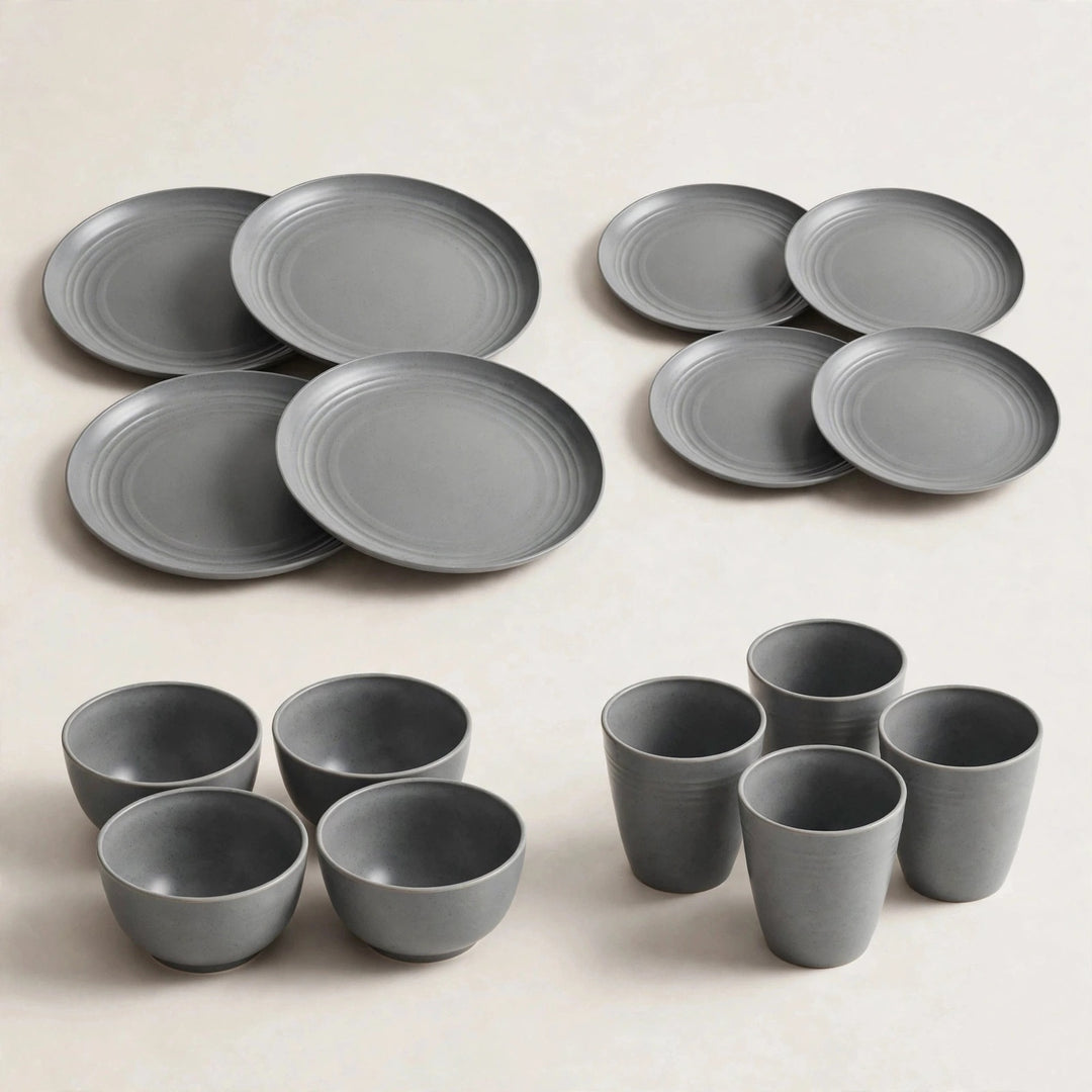 Grey wheat straw dinnerware set with four large plates, four small plates, four bowls, and four cups on a cream background.