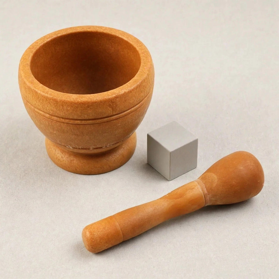 Brown wooden mortar and pestle arranged separately beside a small grey cube on a light grey background.