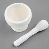 A white marble mortar and pestle set on a neutral gray background.