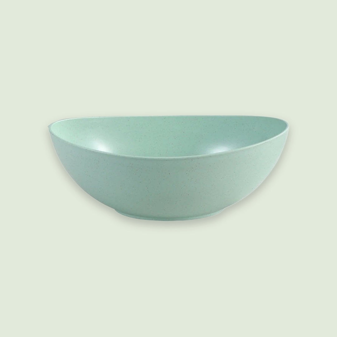 A light mint green ceramic bowl with a subtle speckled texture, shown against a solid pale sage green background.