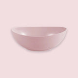 A dusty pink ceramic bowl with a matte, speckled finish, shown from a side angle against a solid, slightly darker pink background.