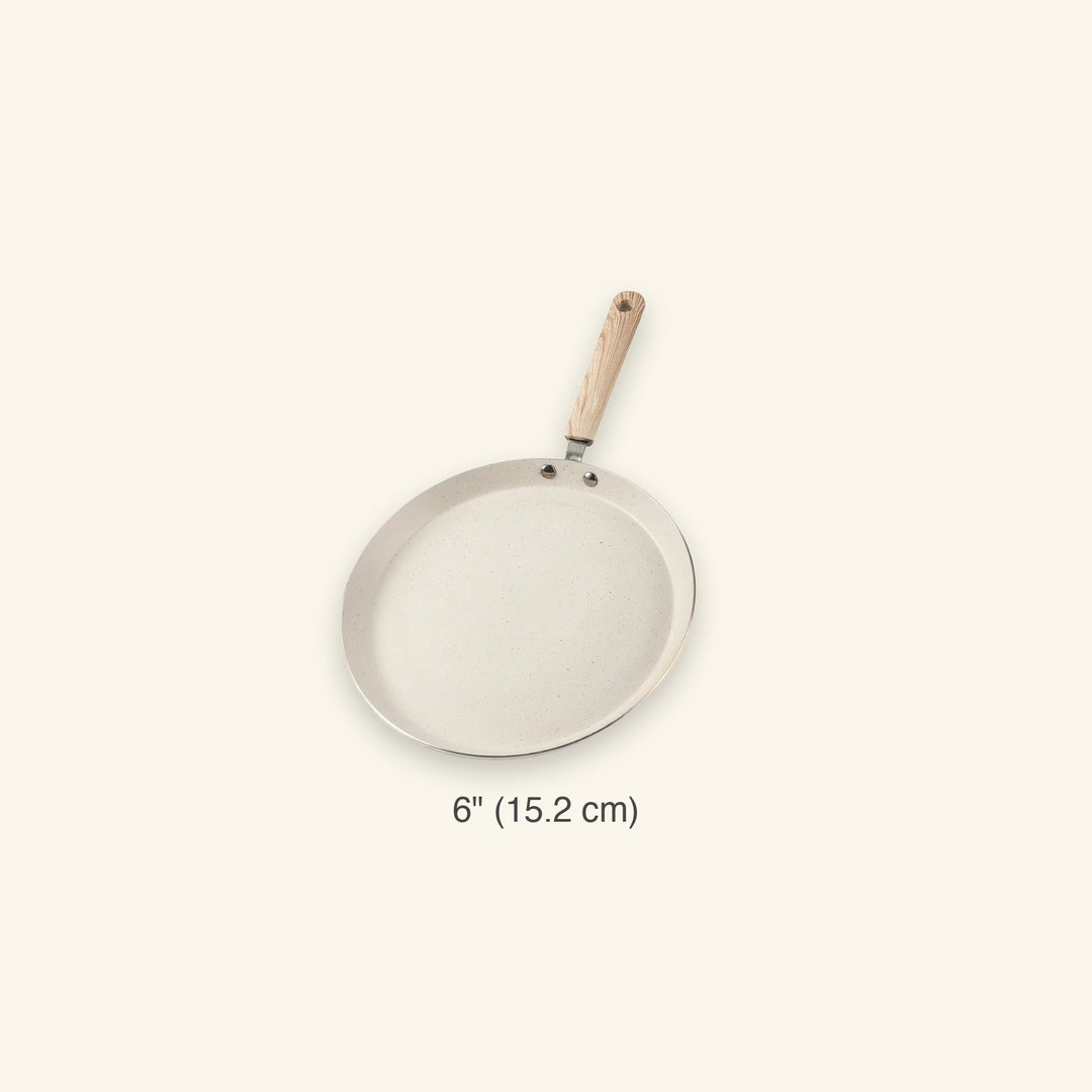 A 6-inch round frying pan with a light beige non-stick coating and a light wood handle, shown against a solid cream background with a size label below.
