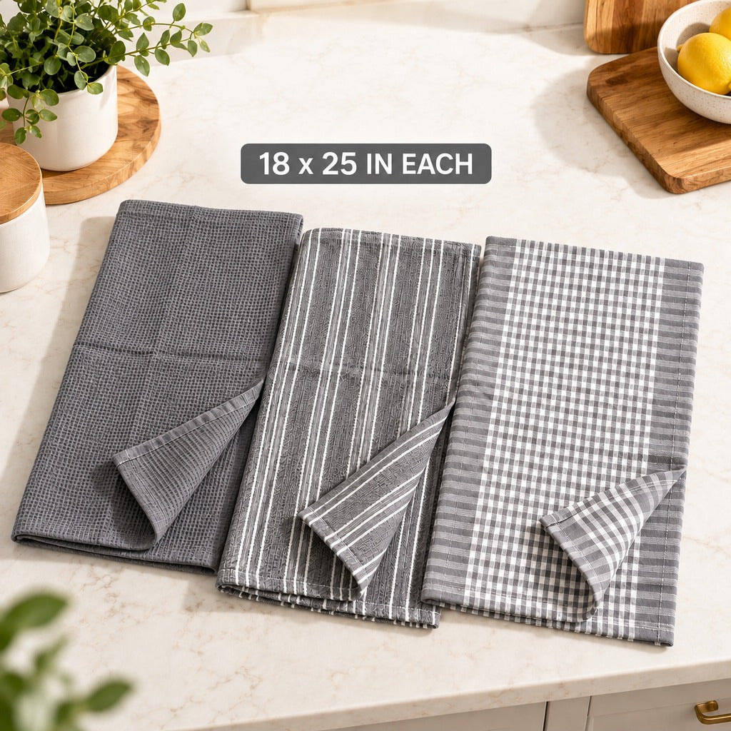 Three folded gray kitchen towels with different patterns are displayed on a light marble countertop. The left towel is solid gray, the middle towel has thin white vertical stripes, and the right towel has a gray and white gingham check pattern.