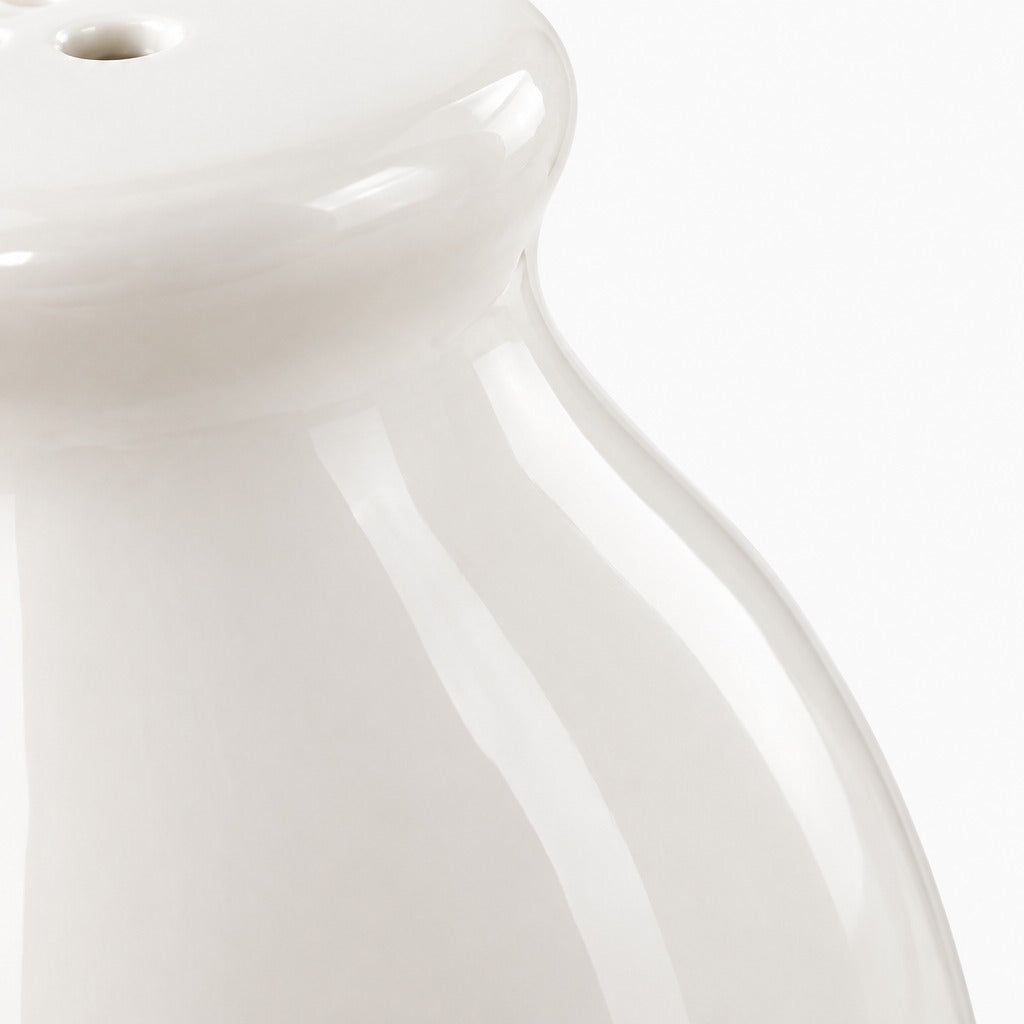 Close-up of a glossy white ceramic vessel, showing the top rim and curved body against a white background.