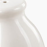 Close-up of a glossy white ceramic vessel, showing the top rim and curved body against a white background.